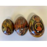 Three Russian lacquered eggs decorated with icons and other religious decoration, hand painted and