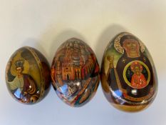 Three Russian lacquered eggs decorated with icons and other religious decoration, hand painted and