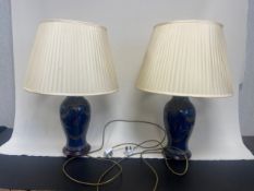 A pair of Chinese baluster form vases hand decorated with foliate motifs on carved hardwood bases.