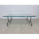 A contemporary dining table with heavy plate glass top on wrought iron trestle supports. H.42 W.