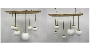 A pair of mid-century vintage brass chandeliers with white glass globe pendant light fittings,
