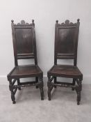 A pair of 17th century oak dining or hall chairs with carved cresting above panel backs and seats on