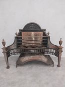 A Regency pierced steel fire grate with swag and urn decoration and brass urn finials on square