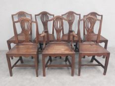 A set of seven Georgian oak and elm dining chairs with pierced splat backs above panel seats on
