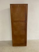 A mid-century oak wardrobe with single panelled door enclosing hanging section with maker's