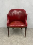 An early 19th century mahogany library tub armchair upholstered in burgundy leather raised on turned