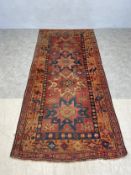 A Shirvan carpet with repeating star medallions on a burgundy ground within stylized foliate