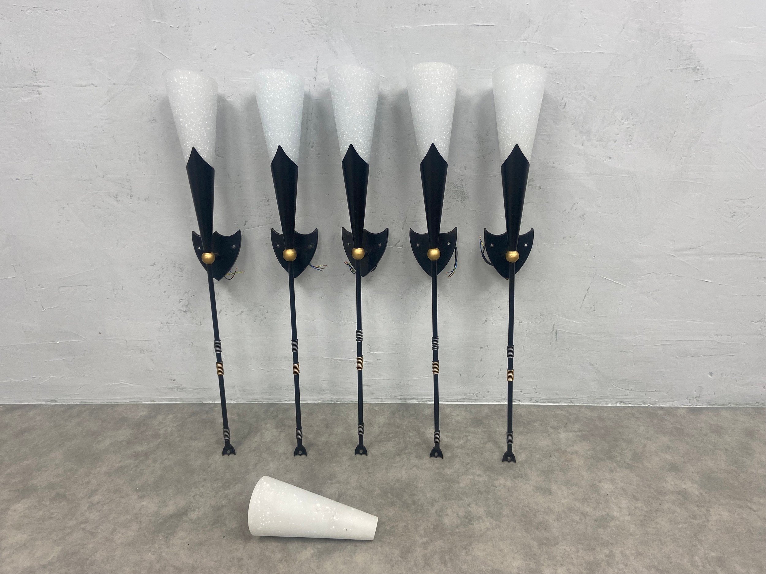 A set of five metal wall lights in the form of heraldic torches with 6 white glass Christopher Wray