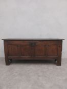 An 18th century oak coffer of panelled construction with stile supports fitted with candlebox. H.