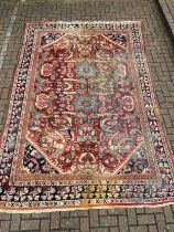 A hand knotted Heriz carpet with flowerhead medallions on a burgundy ground contained within