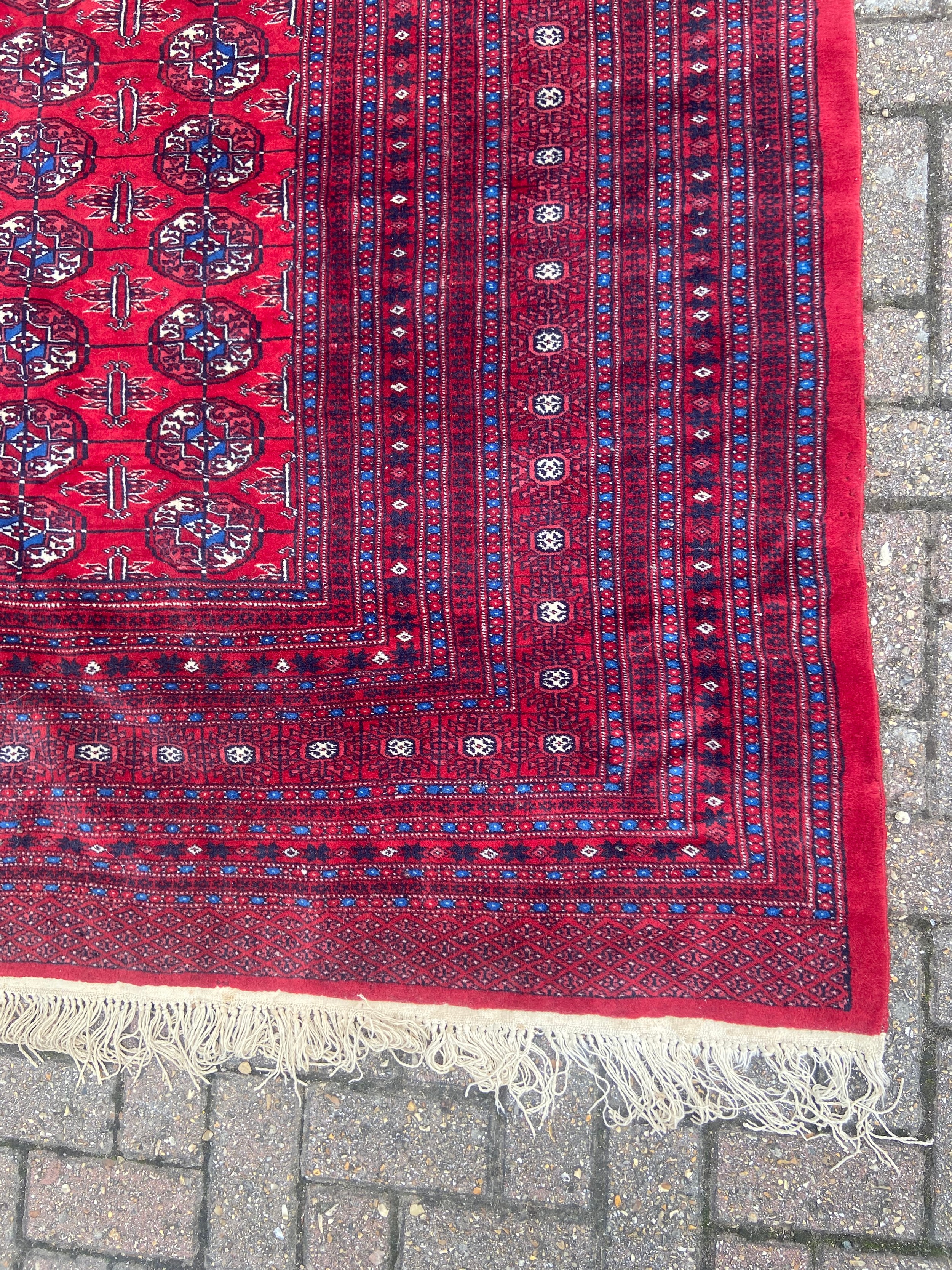 A large bokhara carpet with repeating gul motifs across a burgundy field within multiple stylised - Image 2 of 4
