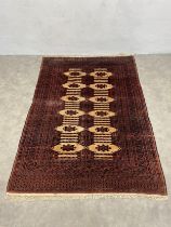An Eastern rug with repeating lozenge medallions on a sand ground within burgundy multiple