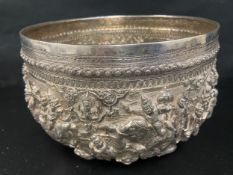 A large antique Burmese silver bowl richly embossed and chased with figures and elephants,