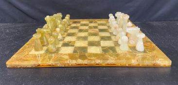 A vintage polished onyx chess set and the matching chessboard. 50x 50cm