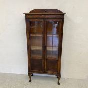 A mid-century oak bookcase having a shaped gallery back and thumb moulded cornice over a pair of