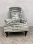 A contemporary armchair in Edwardian style on shaped tapering supports on casters. H.106 W.81cm.