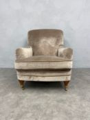 A contemporary Howard style armchair on turned mahogany supports terminating in brass cup casters.