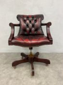 A 19th century style swivel action captain's desk chair in deep buttoned upholstery on five spoke