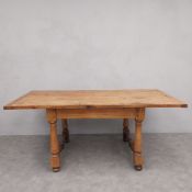 A late 19th century pine dining table with planked top with cleated ends on turned stretchered