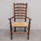 A 19th century elm Lancashire ladder back dining armchair with rush seat on turned stretchered