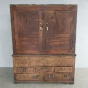 An 18th century two part oak hall cupboard or wardrobe, the upper section fitted with rail and