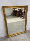 A large contemporary wall mirror with bevelled plate in foliate gilt frame. 137x106cm.