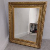 A large 19th century style wall mirror with a rectangular plate in a heavy gilt fluted and scrolling