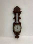 A late 19th century barometer with thermometer in a carved oak case. H.91cm.