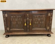 A 19th century oak side cabinet with a plank top over a pair of carved cupboard doors flanked by