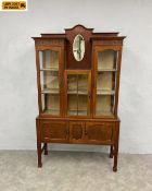 An Edwardian mahogany display cabinet on stand having a superstructure with three glazed vitrines