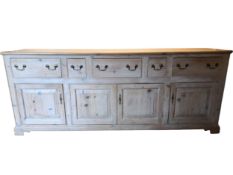 A large early 20th century pine dresser base fitted with drawers above panelled doors on bracket