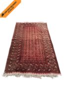 A Belouch carpet with repeating flowerhead motifs across a burgundy field within multiple stylised