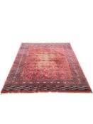 A large Bokhara carpet with repeating gul motifs on a burgundy field within stylised flowerhead