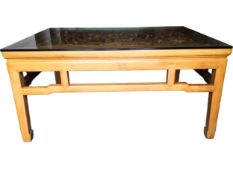 A contemporary Chinese hardwood low table with profusely carved central panel and plate glass top.