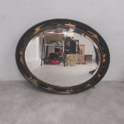 An early 20th century wall mirror with original oval bevelled plate in a black lacquered and gilt