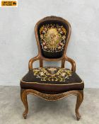 A Victorian walnut framed spoonback nursing armchair with carved cresting over a needlework tapestry