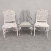 A pair of vintage white painted faux bamboo and rattan chairs, one having a reupholstered faux