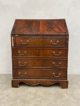 A Georgian style mahogany writing bureau with gilt and tooled green leather lined fall front