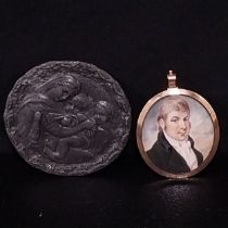 An early 19th century miniature oil portrait of a gentleman in an oval convex glazed yellow metal
