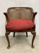 An early 20th century mahogany Georgian style tub bergere armchair on shell carved cabriole