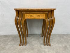 An early 20th century nest of three walnut occasional tables each having a quarter veneered top