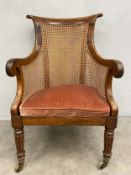 A George IV rosewood framed bergere library armchair with caned back and sides on tapering reeded