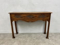 An early 20th century Arts and Crafts style oak console table with plank top over a carved and