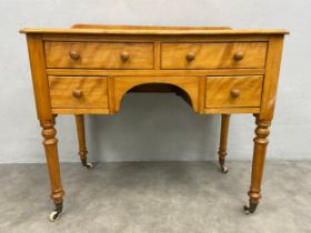 A mid century satin birch kneehole writing or dressing table with an arrangement of drawers on