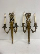 A pair of French 19th century gilt bronze wall sconces each with ribbon cresting over a flame finial