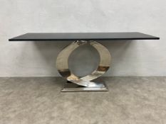 A vintage console table with slate painted top raised on a curved and faceted base on a canted