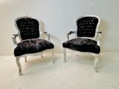 A pair of Louis XV style fauteuil armchairs in deep buttoned black velvet upholstery and carved