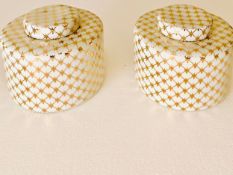 A pair of porcelain lidded jars painted with allover criss-cross gold decoration on white