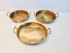 A set of three vintage brass graduating twin-handled trays or pans. 60x50cm. (Largest).