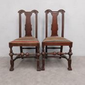 A pair of early 18th century oak dining chairs with shaped splat above tapestry upholstered seats on